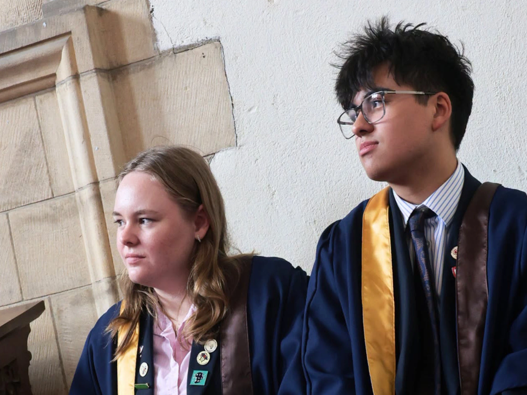 Two students listening during speech at prize giving ceremony.