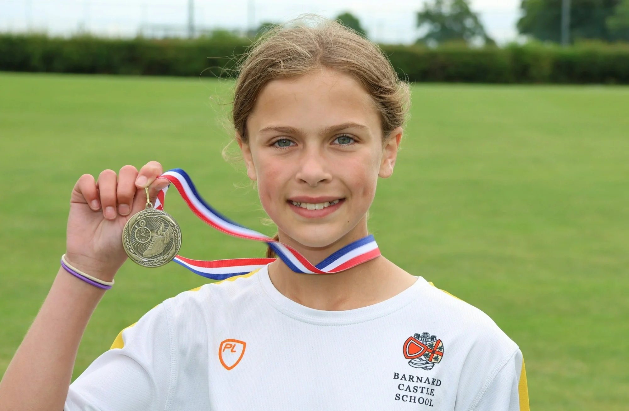 Elsie holding her medal and smiling after breaking records on sports day.