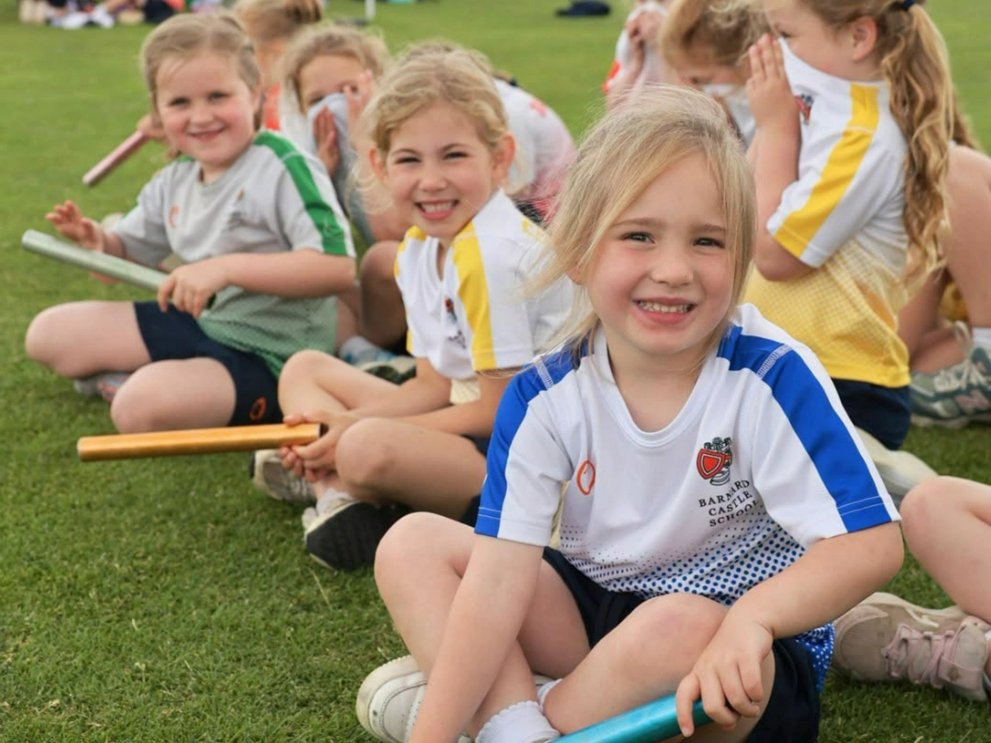 Young Pre School students sat waiting for the relay race on sports day.