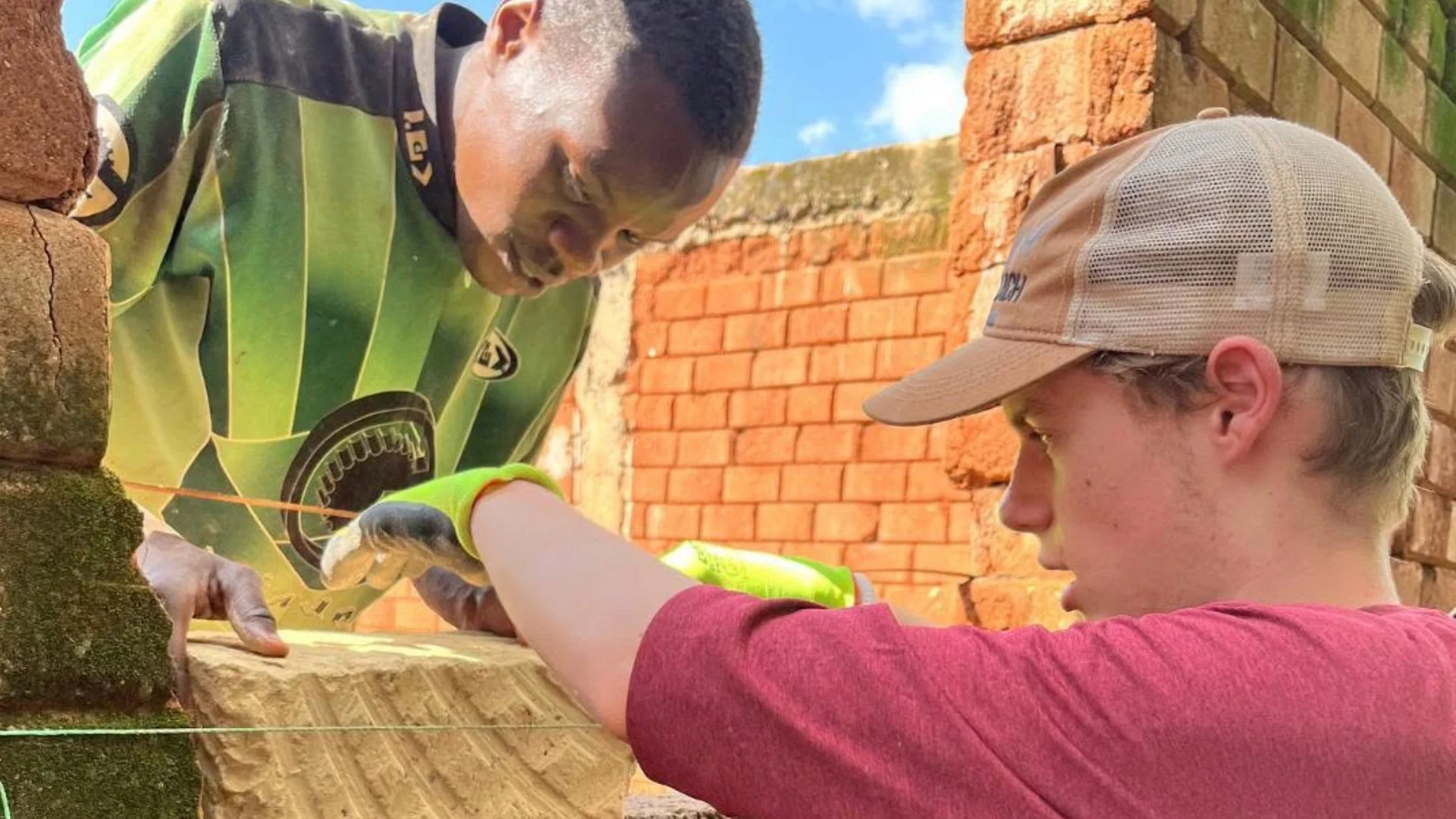 A Barney student helps a local laying bricks in Kenya.
