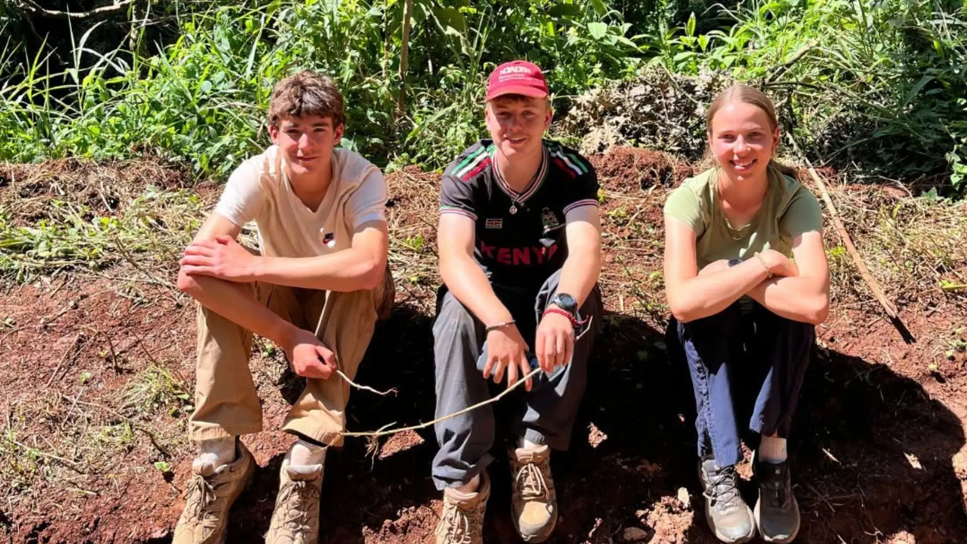 A group of Barney students sitting on a dirt path in Kenya.