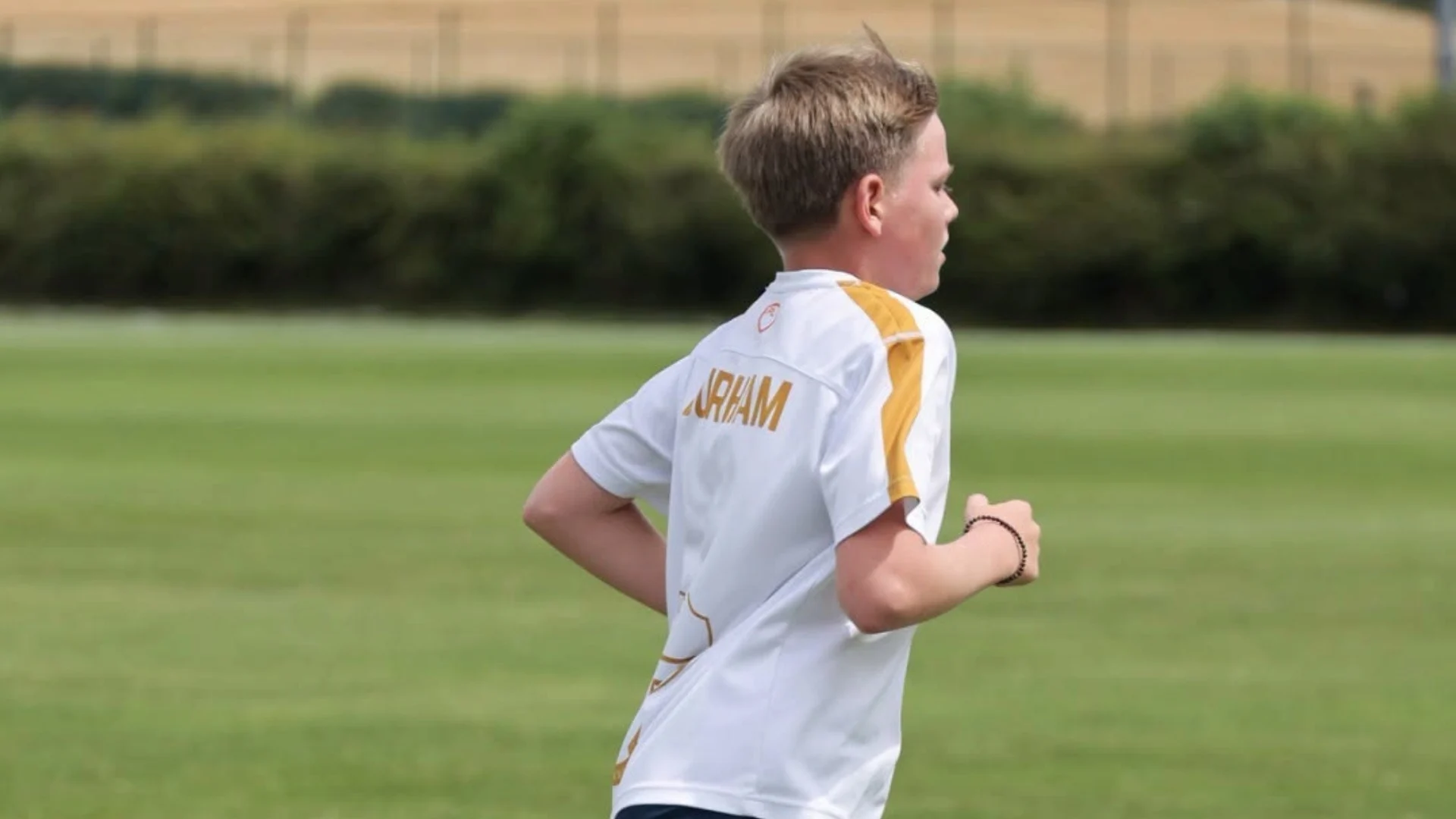 A Senior boy running on the school field.