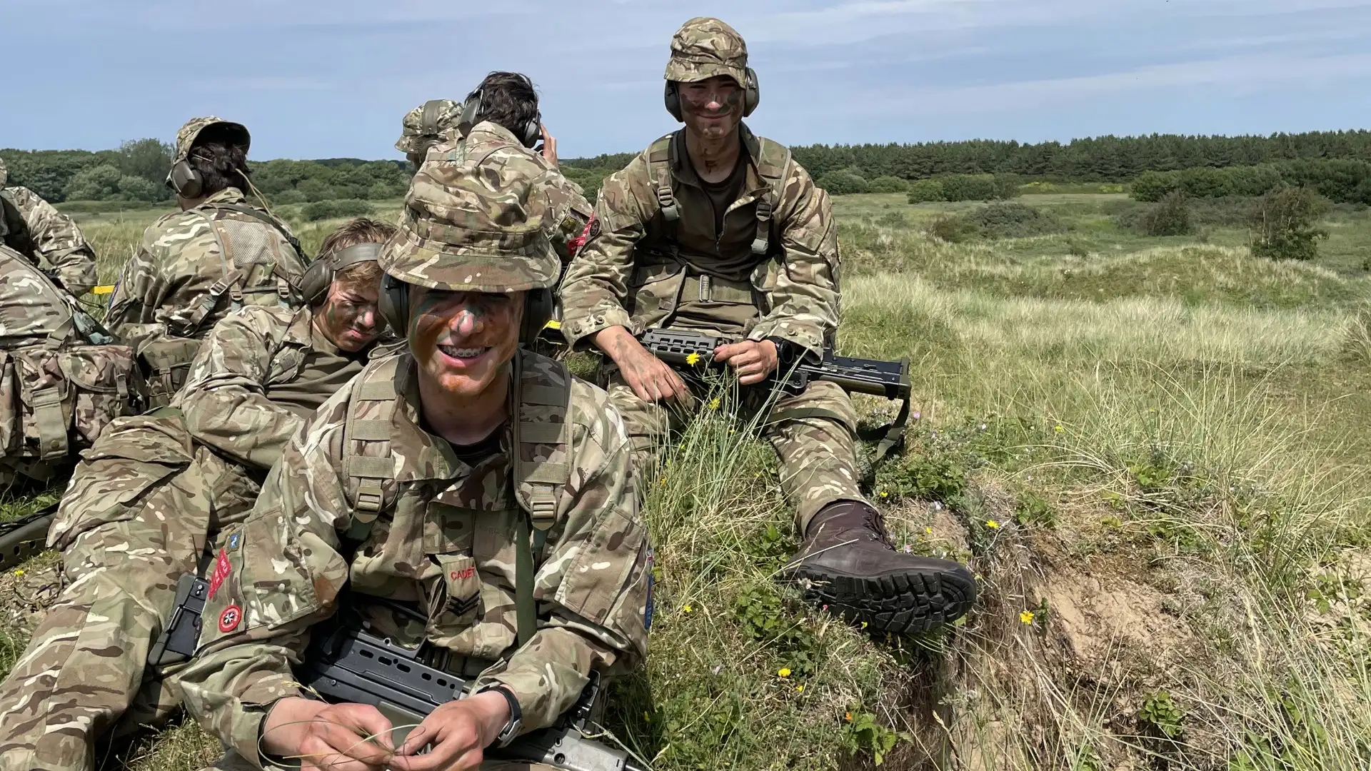CCF cadets sitting in the grass with assault rifles.